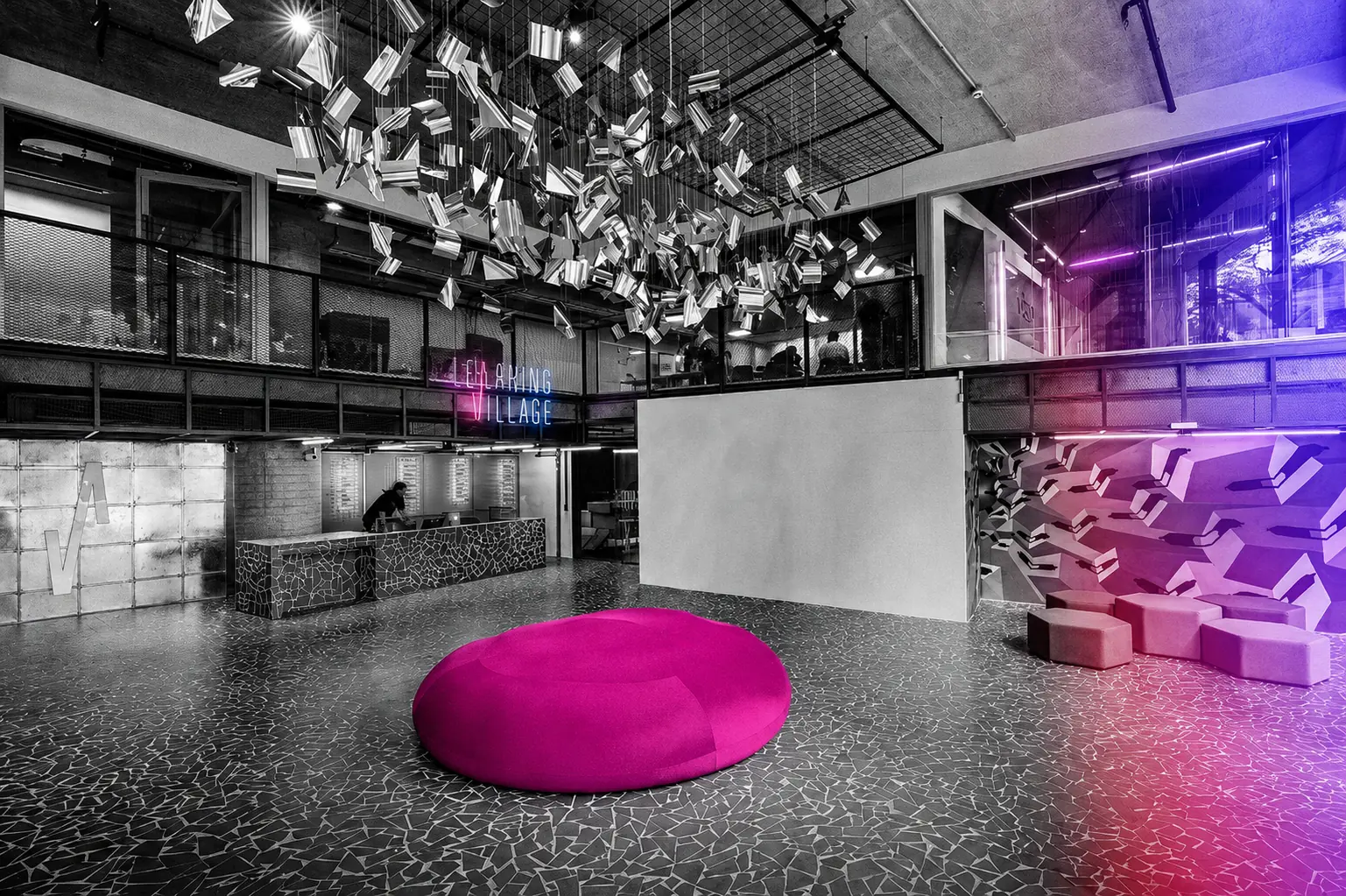 Interior do Learning Village em preto e branco, atravessado por luzes magenta e azul